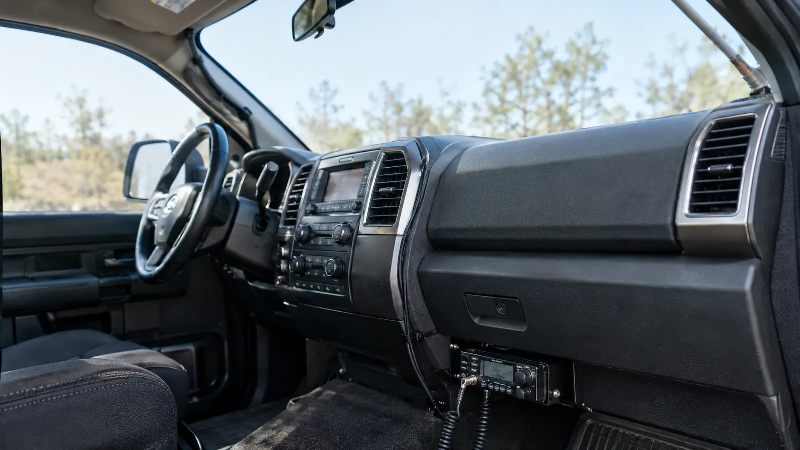 A roll of coaxial cable laid out along a truck bed with a radio under the dash