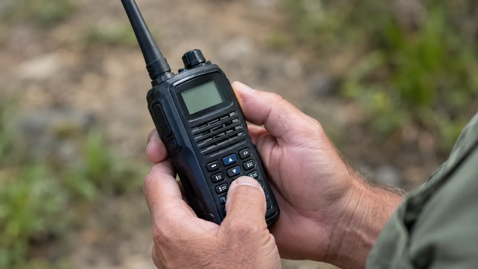 Hands holding a handheld radio while looking at the display